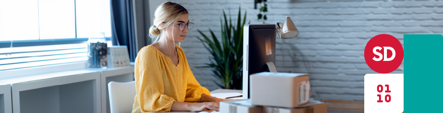 Person working at a modern desk with a computer and a minimalist, well-lit office space.

